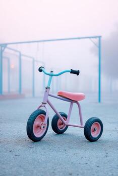 Child's tricycle in an empty foggy playground, showcasing vibrant colors and a nostalgic atmosphere, evoking memories of childhood play and adventure in a serene setting photo