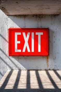 Glowing red emergency exit sign illuminated against a textured wall, casting shadows on the ground, creating a dramatic atmosphere in an abandoned space with copy space photo