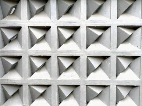 Concrete ventilation blocks forming a grid of recessed diamonds with clean lines and soft shadows in neutral light for modern architectural texture photo