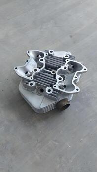 Engine cylinder head, a crucial component of internal combustion engines, displayed from an overhead perspective on a textured gray surface photo
