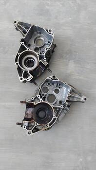 Two metallic engine casing components with complex internal structures displayed against a textured grey surface photo