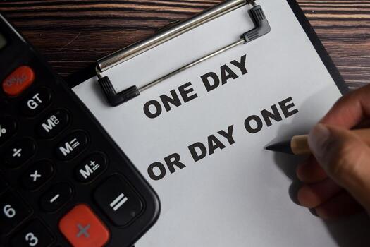 Concept of one day or day one write on clipboard isolated on Wooden Table. photo