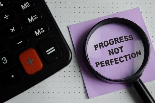 Concept of progress not perfection write on sticky notes isolated on Wooden Table. photo