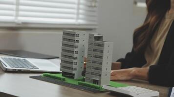 A woman is working on a computer with a model of a building video