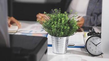 uma plantar dentro uma Panela senta em uma escrivaninha Próximo para uma relógio video