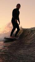 ein Surfer im Bewegung. Erfassen das dynamisch Geist von Surfen beim Sonnenuntergang, mit Wellen abstürzen und ein erfahren Surfer ausführen anmutig bewegt sich auf das Wasser Oberfläche video