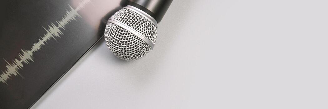 Dynamic microphone on white table with sound waveform print and black background. photo