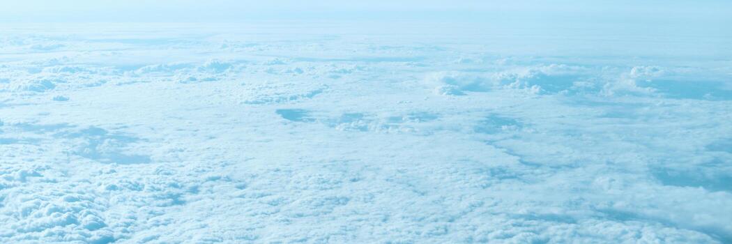 Expansive aerial view of cloudy sky and atmosphere from above with soft blue hues and cloud patterns. photo