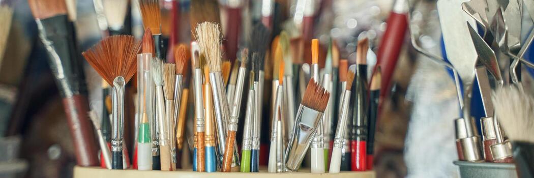 Assorted paintbrushes in a holder displaying various shapes and sizes in an artists studio. photo