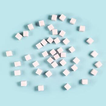Scattered sugar cubes on light blue background in random pattern. photo