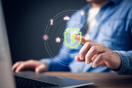 A businessman interacts with a futuristic cybersecurity interface on a laptop, featuring a glowing green shield with a keyhole, symbolizing online security, data protection, and digital privacy. photo