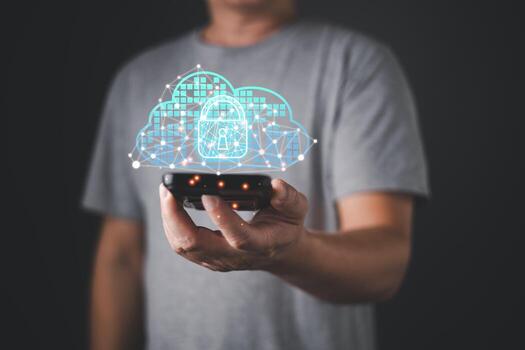 A person in a gray shirt holds a smartphone displaying a glowing cloud with a lock icon, symbolizing computer security, cloud solution, backup, and digital network data protection technology. photo