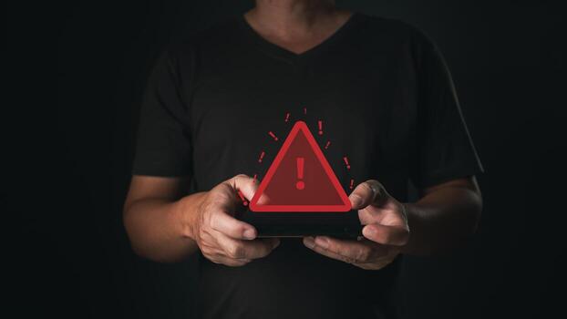 A smartphone user receives a caution notification as a glowing red warning symbol appears, indicating a potential error or alert in the digital system. photo