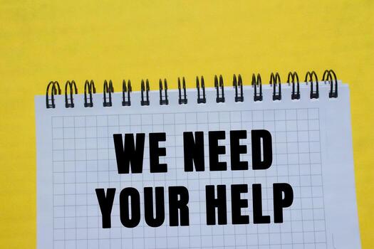 We need your help message written on notebook page on yellow background. Conceptual we need your help symbol. Copy space. photo