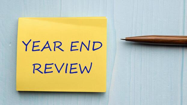 Year end review note on yellow sticky pad with pen on wooden desk new ideas and reflection for business and personal growth photo