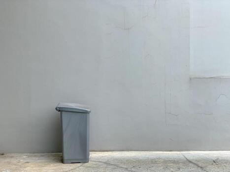 Minimalist Gray Trash Can Against a Plain Concrete Wall. photo