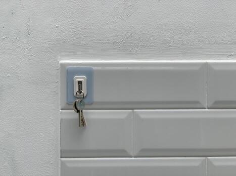 Closeup of a key hanging from a white electrical panel on a textured wall. photo