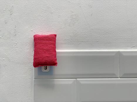 Red rectangular object on a white tiled wall, minimalist and clean design. photo