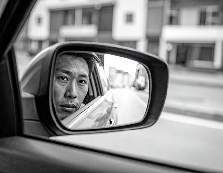 Man looking in rearview mirror while sitting in car during a calm afternoon drive in an urban setting photo