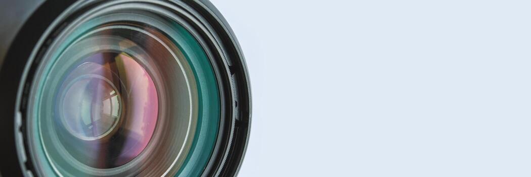 Close-up of camera lens with multicolored reflections and soft blue background. photo