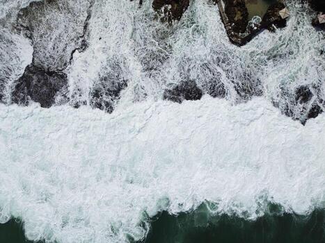 Top View of Sea Waves Breaking on Rocks, Dramatic Ocean Texture and Foam Pattern photo