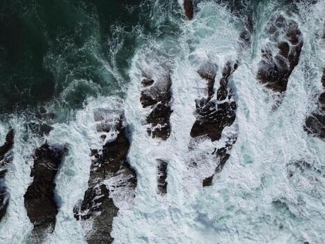 Drone Shot of Rough Sea and Rocks, Powerful Ocean Waves Splashing on Rugged Coastline photo