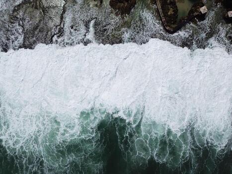 Aerial View of Ocean Waves Crashing on Rocky Shore, Powerful Sea Texture Background photo