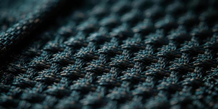 Macro detail of a coarsely woven synthetic fabric in dark teal and black. Repeating knit pattern with sharp focus and subtle texture photo