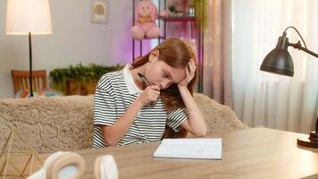 bambino ragazza seduta a casa tavolo fa compiti a casa con taccuino Aperto pensieroso guardare per i problemi soluzione. scuola ragazzo felicemente trova corretta Rispondere, animatamente sorridente, esclamando gioioso capire video