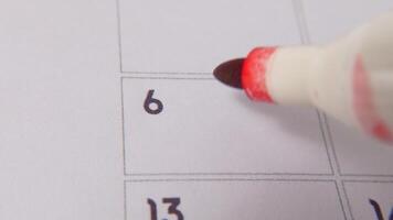 The 6th on the calendar is circled in red marker in a close-up macro shot on a white page, symbolizing an important day or reminder. video