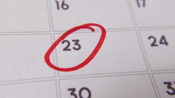 il 23 su il calendario è cerchiato nel rosso marcatore nel un' avvicinamento macro tiro su un' bianca pagina, simboleggiante un importante giorno o promemoria. video