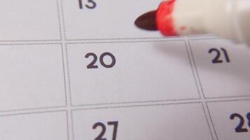 The 20th on the calendar is circled in red marker in a close-up macro shot on a white page, symbolizing an important day or reminder. video