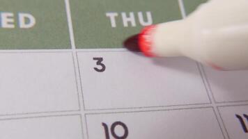 de 3:e på de kalender är ringade in i röd markör i en närbild makro skott på en vit sida, symboliserar ett Viktig dag eller påminnelse. video