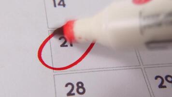 il 21 su il calendario è cerchiato nel rosso marcatore nel un' avvicinamento macro tiro su un' bianca pagina, simboleggiante un importante giorno o promemoria. video