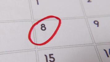 The 8th on the calendar is circled in red marker in a close-up macro shot on a white page, symbolizing an important day or reminder. video