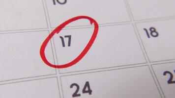 il 17 ° su il calendario è cerchiato nel rosso marcatore nel un' avvicinamento macro tiro su un' bianca pagina, simboleggiante un importante giorno o promemoria. video