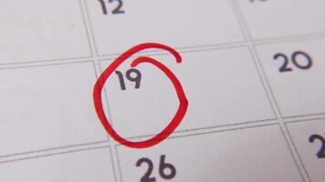 The 19th on the calendar is circled in red marker in a close-up macro shot on a white page, symbolizing an important day or reminder. video