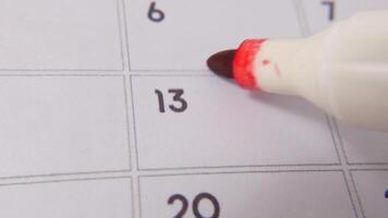 The 13th on the calendar is circled in red marker in a close-up macro shot on a white page, symbolizing an important day or reminder. video