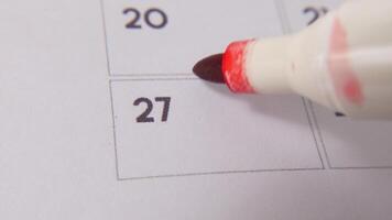 The 27th on the calendar is circled in red marker in a close-up macro shot on a white page, symbolizing an important day or reminder. video