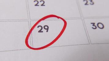 il 29th su il calendario è cerchiato nel rosso marcatore nel un' avvicinamento macro tiro su un' bianca pagina, simboleggiante un importante giorno o promemoria. video