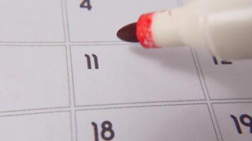 The 11th on the calendar is circled in red marker in a close-up macro shot on a white page, symbolizing an important day or reminder. video