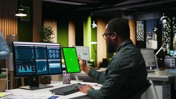 grön skärm på läsplatta Nästa till ung svart affärsman granskning data, arbetssätt på analys Rapportera skrivning och upptäckt lösningar för global expansion och företag förvaltning uppgifter. kamera a. video