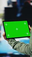 Vertical Green screen tablet used by person to look at internet channels, isolated over digital backdrop. Woman enjoys unlimited metaverse content with mockup device, 360 degrees rotation, camera B video