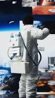 vertikal glad astronaut dans medan övervakning uppdrag data på visas. glad rymdskepp kosmonaut har roligt håller på med dansa rör sig medan ser på Plats resa multimedia digital bakgrund, kamera en video