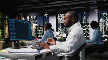 Male black employee focusing on AI virtual assistant usage on monitor, solving problem solving tasks with futuristic tech and machine learning. Communication and IT support. Camera A. video