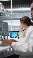 vertikal laboratorium chef övervakar vetenskapsmän arbetssätt på dator, bearbetning dna data. labb team ledare och anställda ser på genetisk analys diagnostik, brainstorming vetenskaplig genombrott, kamera en video