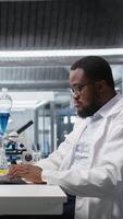 Vertical Lab specialist doing genetics study using clinical equipment, removing eyeglasses, checking analysis results on computer. Man using scientific gear at workbench, doing complex experiments, camera A video