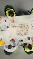 Vertical Top down view zoom in of diverse colleagues consulting on a master plan for urban development. Property developers review architectural software and designs to achieve real estate growth. Camera A. video