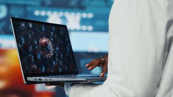 stänga upp av biomedicinsk ingenjör studerar patogener använder sig av bärbar dator till design antiviral strategier. forskare ser på genomer på anteckningsbok skärm, jämförande infektion modeller video