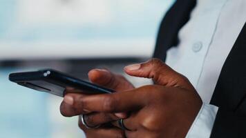 stänga upp av affärskvinna använder sig av telefon till chatt med företag partner, framställning beslut tillsammans. chef textning aktieägare på mobiltelefon efter analyserar nyckel prestanda indikatorer, håller på med planera video